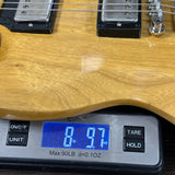 Close-up of a wooden bass guitar body resting on a digital scale displaying 8.97 lbs.