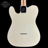 The back of a white electric guitar with a maple body, black control plate, and silver hardware, shown against a black background with a Tone Shop watermark in the top left.