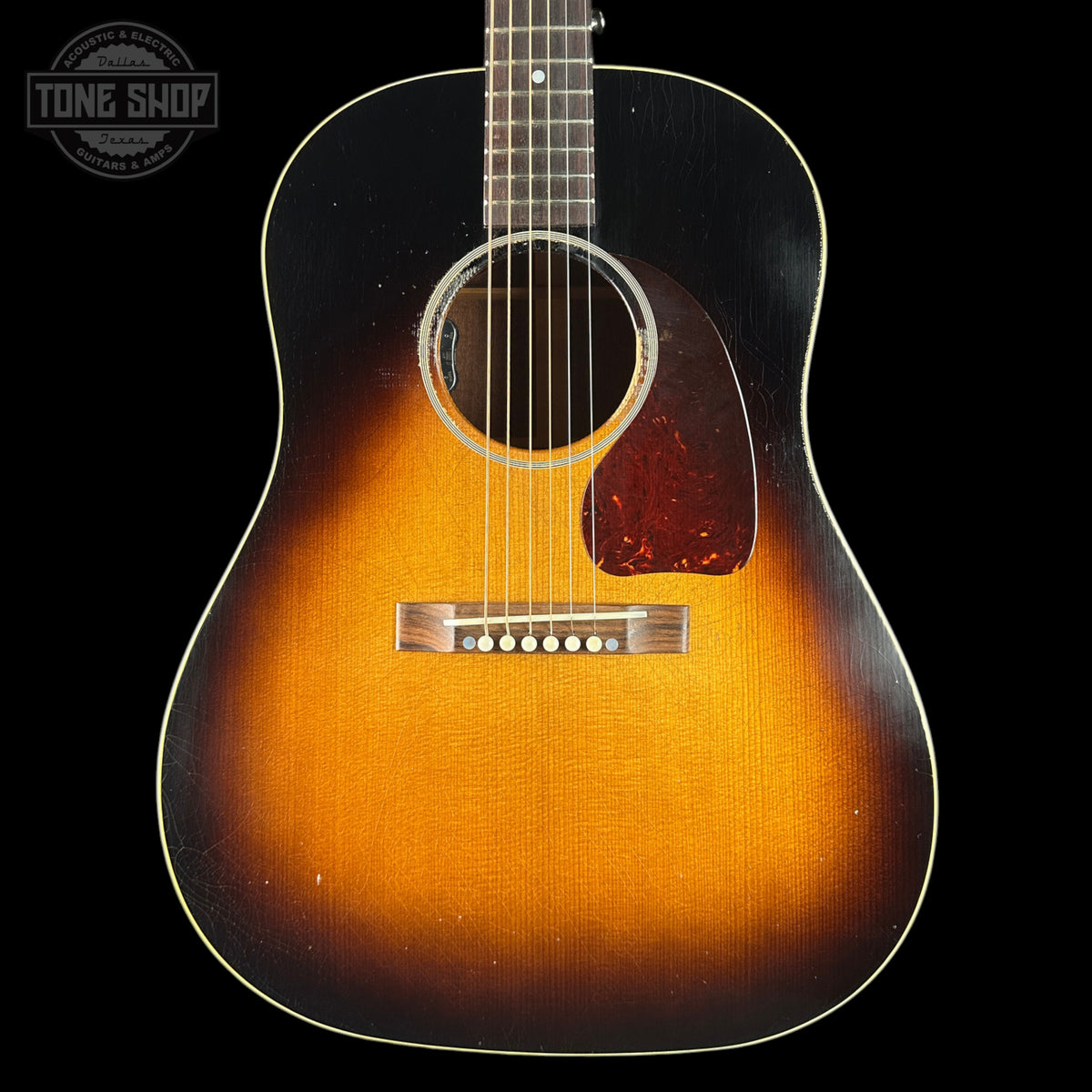 Acoustic guitar with a sunburst finish on a black background, featuring the Tone Shop logo.