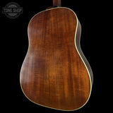 Back view of a wooden acoustic guitar with 'Tone Shop' logo.