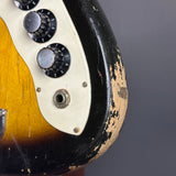 Close-up of a vintage electric guitar with worn finish on a dark background
