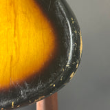 Close-up of a guitar's soundhole with a dark rim and wooden center on a gray background