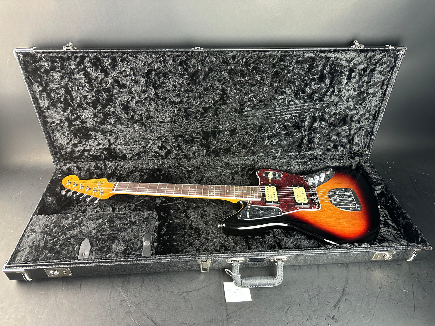 Electric guitar in a hard-shell case on a gray surface