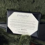 A black leather presentation box containing a Martin Custom Shop Certificate of Authenticity, placed on a dark green textured fur surface.