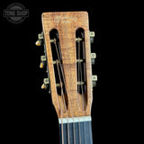 Close-up of a guitar headstock with six tuning pegs, six strings entering a double-cutaway design, and the 'Martin D'Addario' brand name engraved on the wood. The headstock is shown against a solid black background.