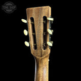 Close-up of the headstock of a wooden acoustic guitar against a solid black background, showing the natural wood grain and six tuning pegs. A 'TONE SHOP' watermark is visible in the top left corner.