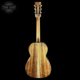 The back view of a wooden acoustic guitar against a solid black background, featuring a natural wood grain finish and a Tone Shop watermark in the top left corner.
