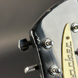 Close-up of a guitar headstock with tuning pegs and brand name on a dark background