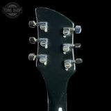 Close-up of a black guitar headstock with tuning pegs on a black background, featuring the Tone Shop logo.