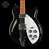 Black electric guitar with white pickguard on a black background, featuring the Tone Shop logo.