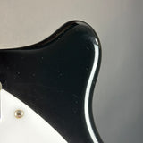 Close-up of a black guitar pickguard with a white border on a gray background