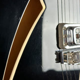 Close-up of a guitar with a black body and brown pickguard.