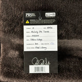 A black and white product tag for aPRS Music Gear McCarty 5th Tremolo guitar strings, showing handwritten details and a signature on a dark brown textured background.