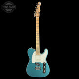 Blue electric guitar with a white pickguard on a black background, featuring the Tone Shop logo.