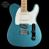 Blue electric guitar with a white pickguard on a black background, featuring 'Tone Shop' branding.