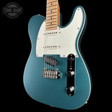 Blue electric guitar with a white pickguard on a black background, featuring 'Tone Shop' branding.