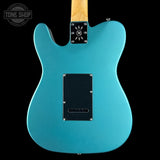 Teal electric guitar with a black pickguard on a black background, featuring 'Tone Shop' branding.