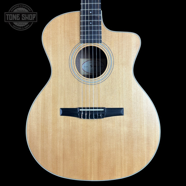 A front-facing acoustic guitar with a natural wood finish and a black cutaway body, shown against a solid black background with a Tone Shop watermark in the top left corner.