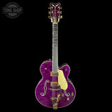 Purple electric guitar with gold hardware on a black background, featuring 'Tone Shop' logo.