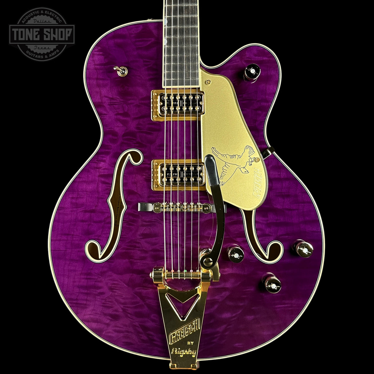 Purple electric guitar with gold hardware on a black background, featuring the Tone Shop logo.