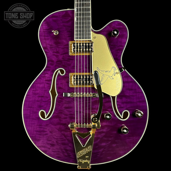 Purple electric guitar with gold hardware on a black background, featuring the Tone Shop logo.