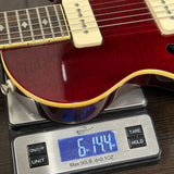 Red electric guitar on a digital scale displaying weight