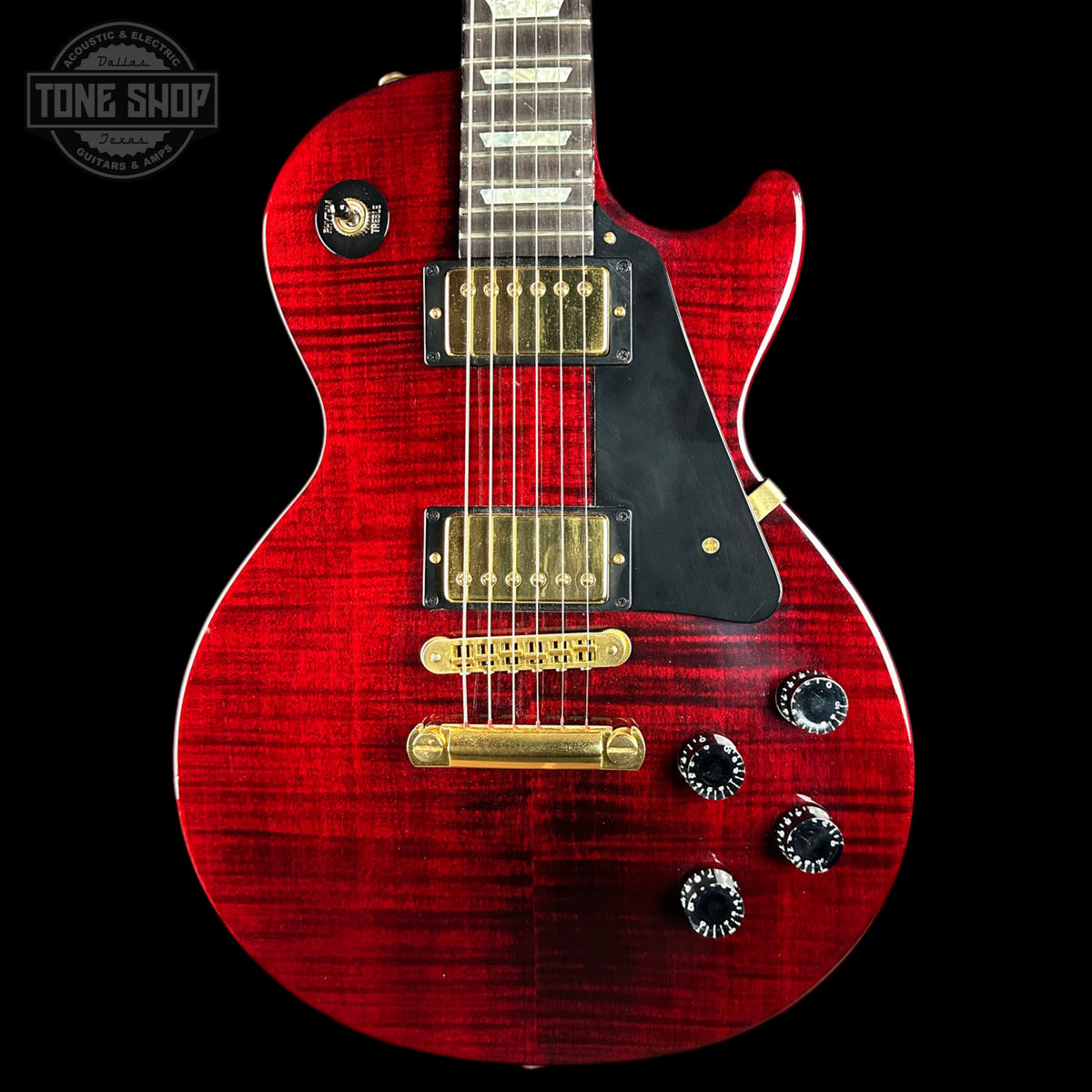 A red Gibson Les Paul Custom electric guitar with a flamed maple top, black pickguard, gold humbucker pickups, and black control knobs, shown against a solid black background with a Tone Shop watermark in the top left corner.