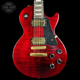 A red Gibson Les Paul Custom electric guitar with a flamed maple top, black pickguard, gold humbucker pickups, and black control knobs, shown against a solid black background with a Tone Shop watermark in the top left corner.