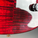 Close-up of a glossy red electric guitar body showing the wood grain finish, a white pickguard, and part of a black control knob against a neutral gray background.