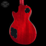 The back of a red electric guitar with a glossy cherry red finish, black pickguard, and gold hardware, shown against a black background with a Tone Shop watermark in the top left.