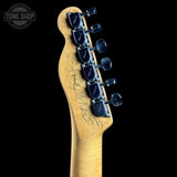 Guitar neck with tuning pegs on a black background, featuring the Tone Shop logo.