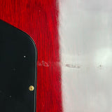 Close-up of a glossy black object corner with a small gold screw against a red and white textured background.