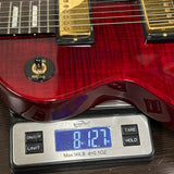 A red electric guitar body resting on a digital scale showing a weight of 8.127 lbs.