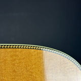 Close-up detail of an acoustic guitar body showing the natural wood grain transition from golden yellow to light beige, bordered by a black and gold chevron inlay against a dark background.