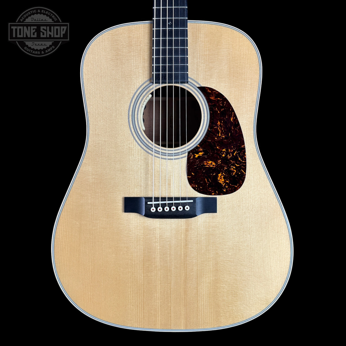 Acoustic guitar with a visible brand logo on a black background