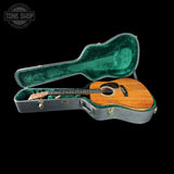 Acoustic guitar in an open case with 'Tone Shop' branding.