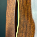 Close-up detail of a wooden object showing a rich dark brown wood grain finish and a thin light-colored edge stripe against a dark background.