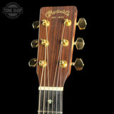 Close-up of a Martin guitar headstock with gold tuning pegs on a black background.