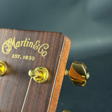Close-up of a Martin & Co. guitar headstock with gold tuning pegs on a dark background