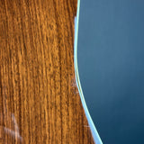 Close-up of a curved edge showing a warm brown wood grain surface on the left and a smooth dark blue surface on the right, separated by a thin light-colored line.