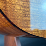 Close-up of a wooden guitar with a blurred natural landscape in the background