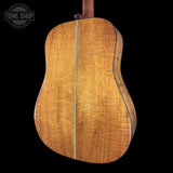 Back view of a wooden acoustic guitar with 'Tone Shop' logo in the corner.