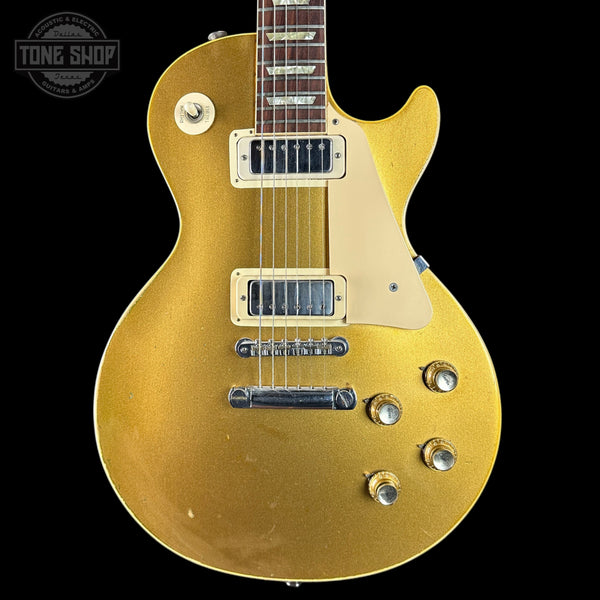 Gold electric guitar with 'Tone Shop' logo in the corner