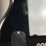 Close-up of a black electric guitar body with a gold-toned pickguard and visible surface scratches and wear.