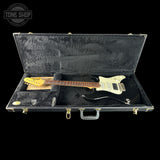 Black electric guitar in a hard-shell case with 'Tone Shop' branding.