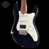 Black electric guitar with a white pickguard on a black background, featuring the Tone Shop logo.