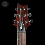 Close-up of the headstock of a Mira acoustic guitar against a solid black background, showing the dark reddish-brown wood, silver tuning pegs, and the Mira logo on the black and white label.