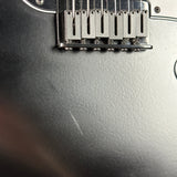 Close-up of a guitar's bridge and tuning pegs on a gray surface