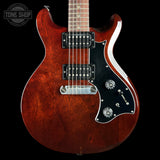 A classic double-cutaway electric guitar with a glossy reddish-brown sunburst finish, black pickguard, and chrome hardware, shown against a solid black background.