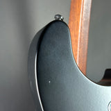 Close-up of a guitar neck with a dark fretboard and wooden fingerboard.